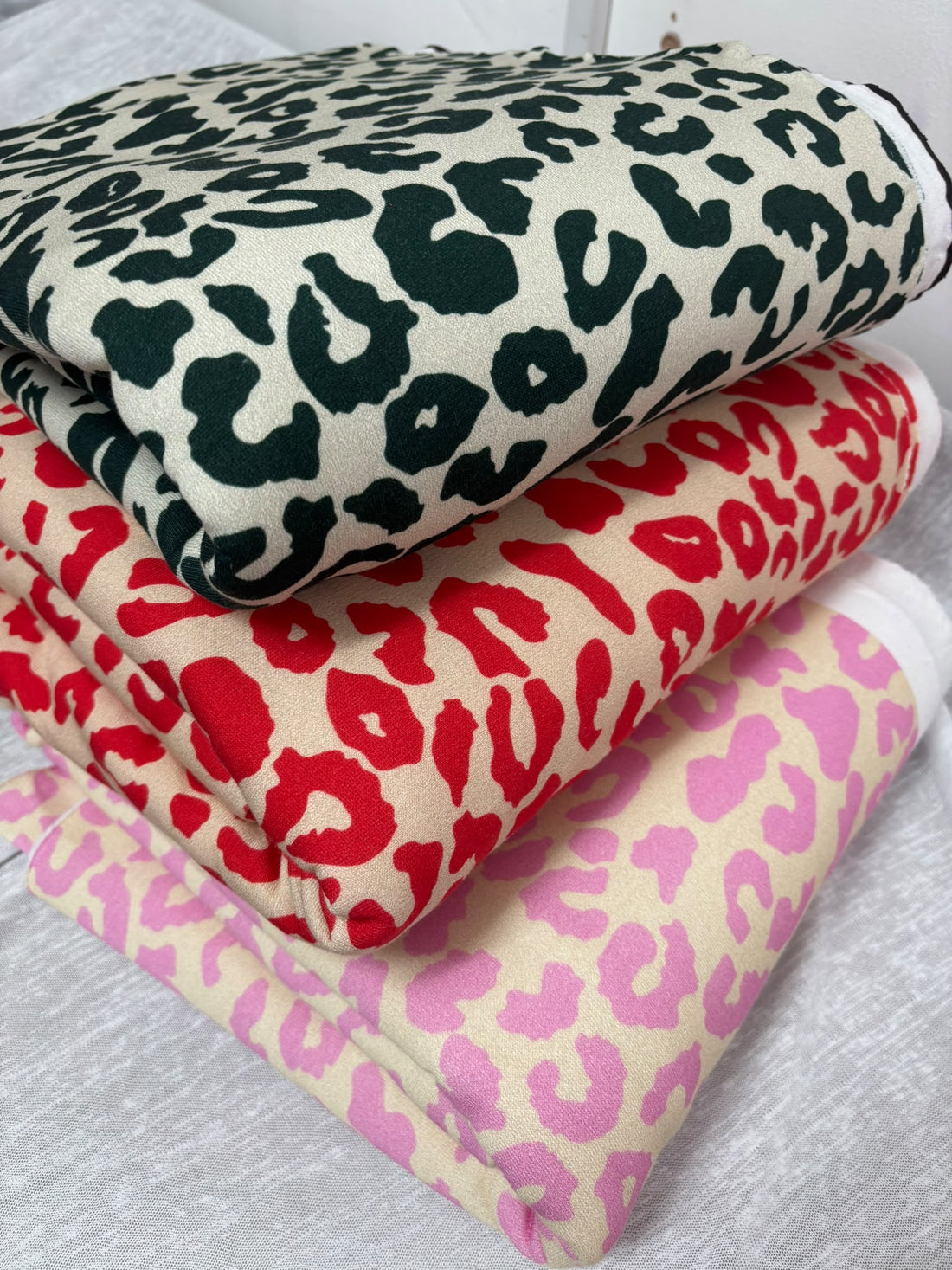 Leopard print brushed back fleece jersey in bottle green, red and pink
